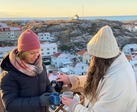 Några kvinnor som står bredvid varandra och fikar utomhus.