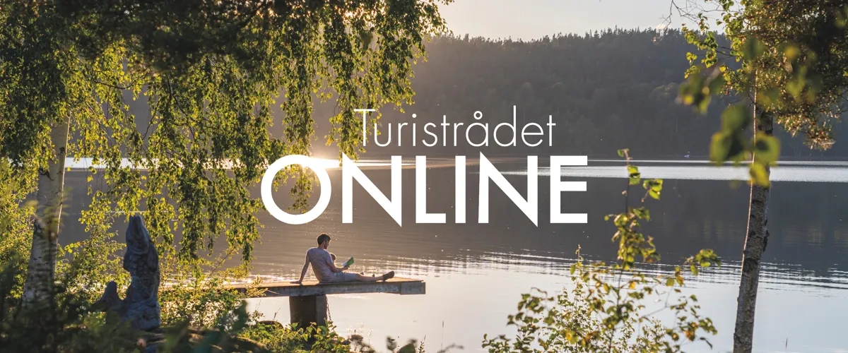 En man sitter på en båt på en sjö.