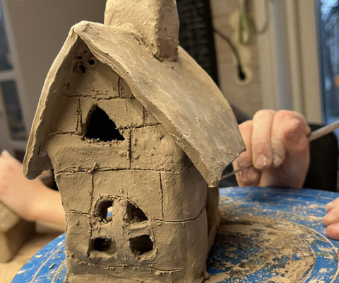 En person gör ett hus av lera.