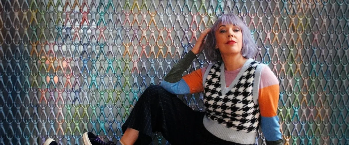 En kvinna sitter på golvet framför en vägg.