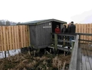 En grupp människor som står runt ett hus i trä.