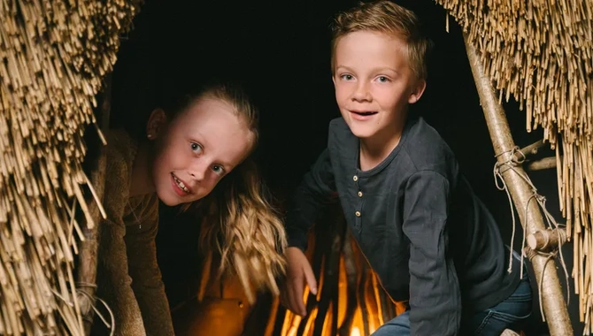 Två barn som kikar ut ur en koja av vass.
