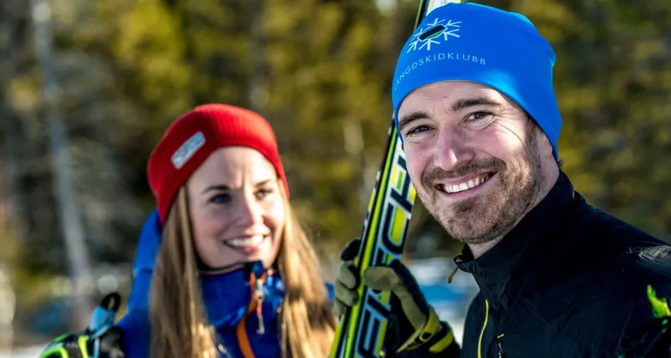 En man och en kvinna håller i skidor i snön.