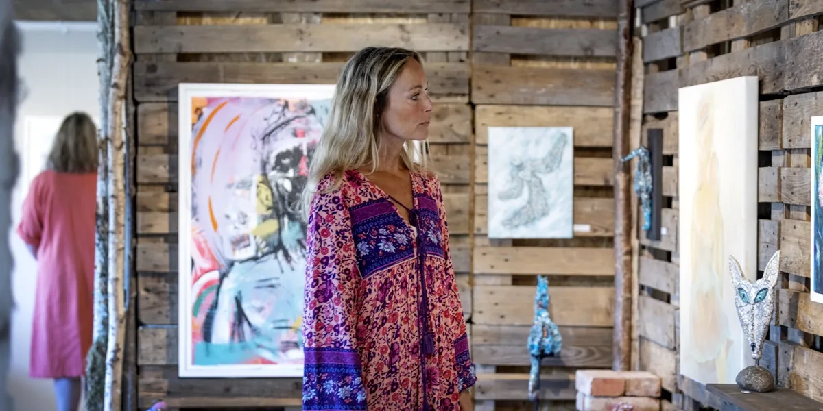 En kvinna står framför en trävägg.