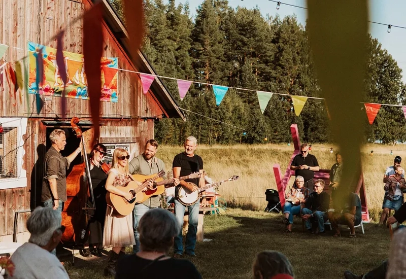 En grupp människor som spelar musik framför en lada.