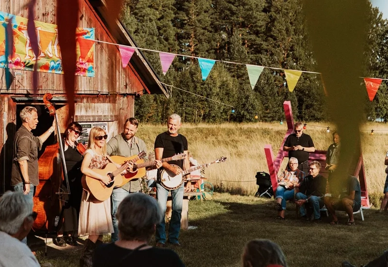 En grupp människor som spelar musik framför en lada.