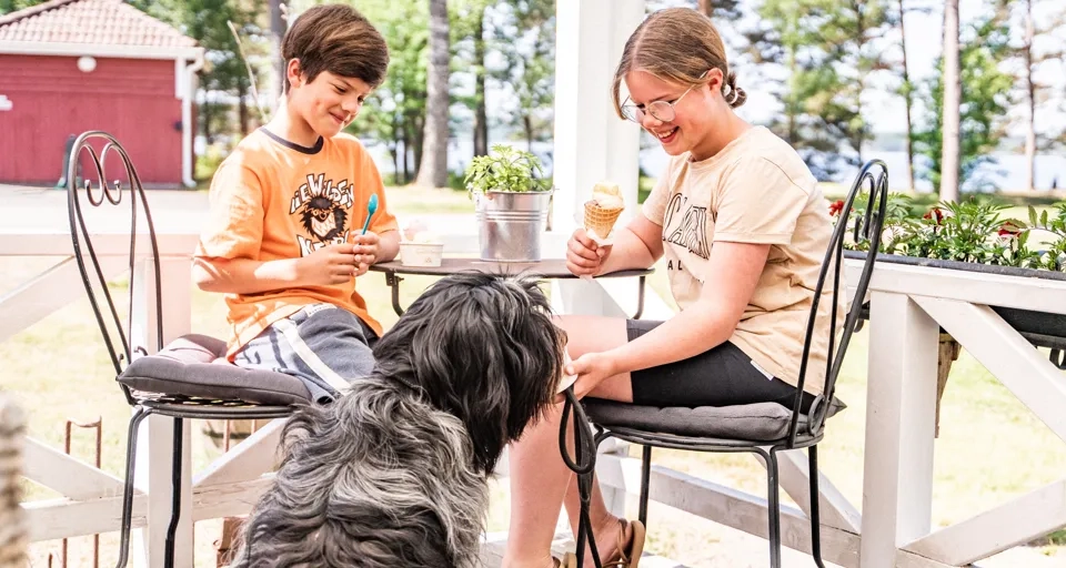 Barn äter glass med en hund vid sidan av bordet.