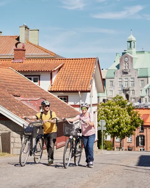 Två personer cyklar i en småstad.