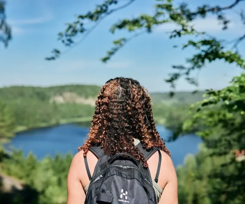 En kvinna med ryggsäck tittar på en sjö.