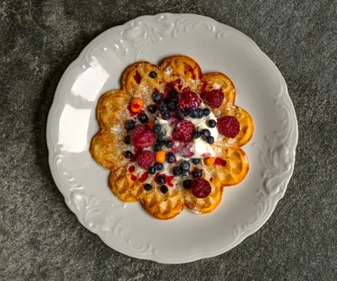 En vit tallrik toppad med våfflor täckta med frukt.