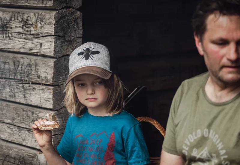 Ein Mann steht neben einem kleinen Mädchen, das ein Stück Essen in der Hand hält.