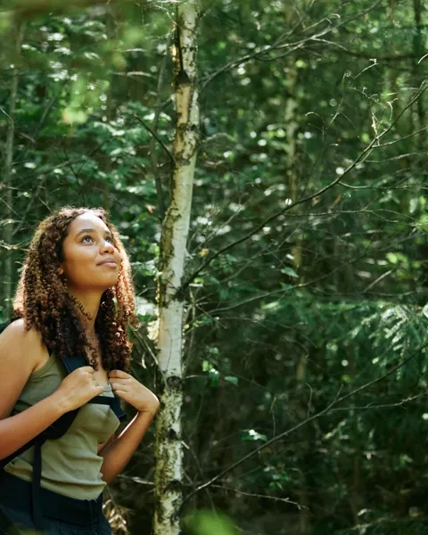 En person som står i skogen med en ryggsäck.