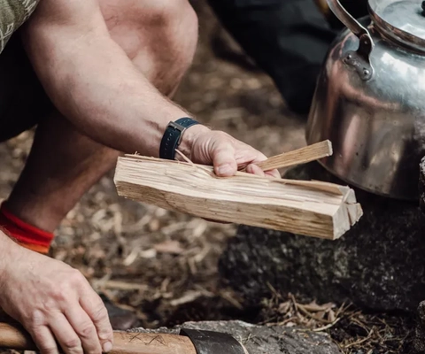 Ein Mann hält ein Stück Holz neben einem Ofen.
