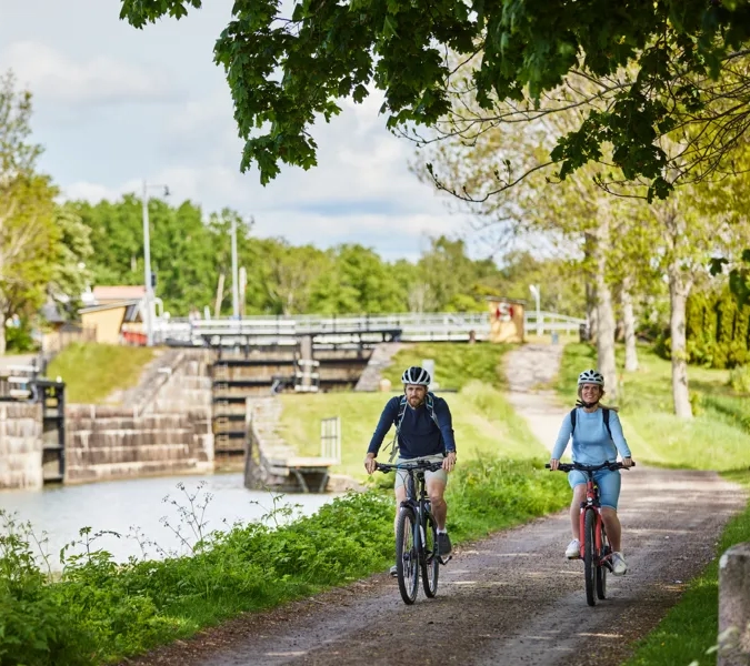 A couple of people riding bikes down a dirt road.