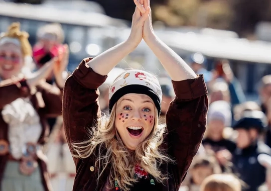 En grupp människor som är utklädda till påskkärringar och håller upp händerna.