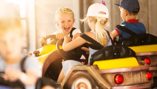 A group of young children riding on top of a toy car.