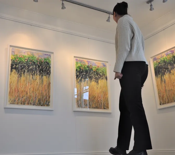 kvinna ser på tavlor i galleri