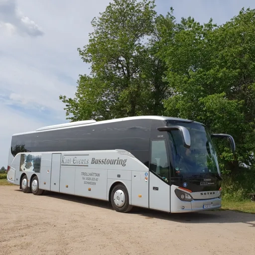 En turistbuss parkerad på en grusväg.