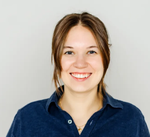 En kvinna i blå skjorta ler.