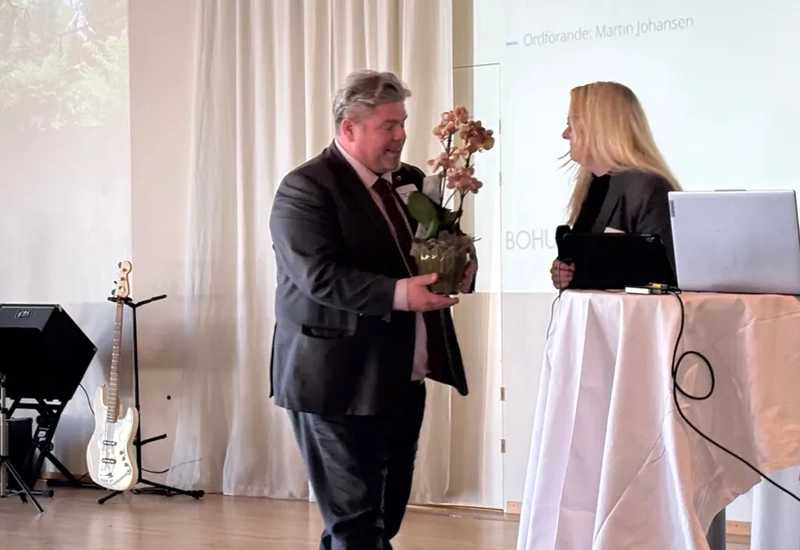 En man i kostym håller i en blombukett.