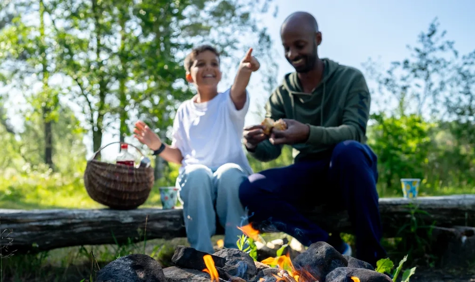 En pappa och ett barn grillar marshmallows över öppen eld.