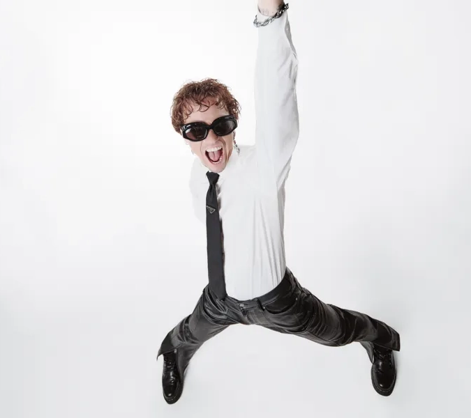 En man i vit skjorta och slips gör ett fredstecken.