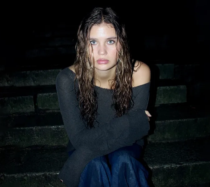 En kvinna sitter på en trappa i mörkret.