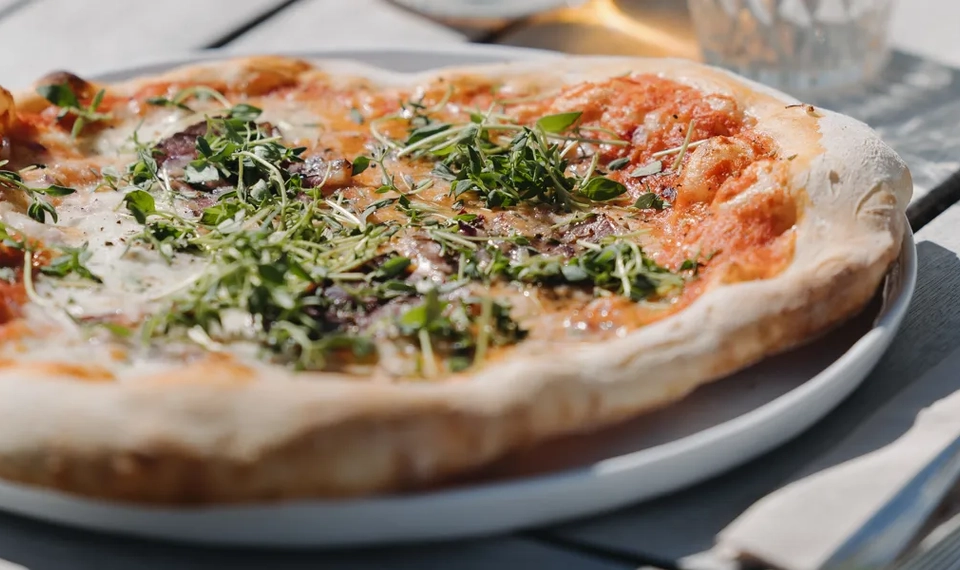 En pizza som ligger på en vit tallrik.