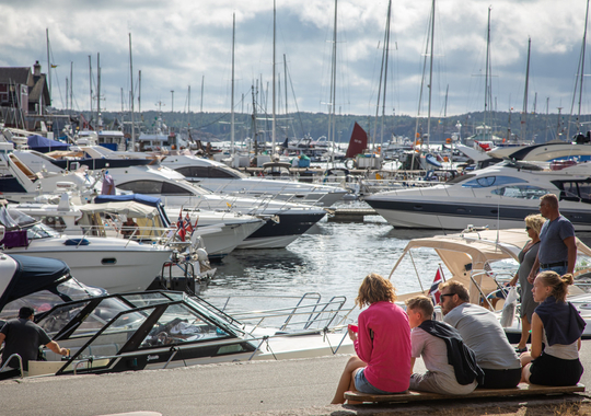 Familj sitter vid strandpromenaden och tittar på båtar i hamnen