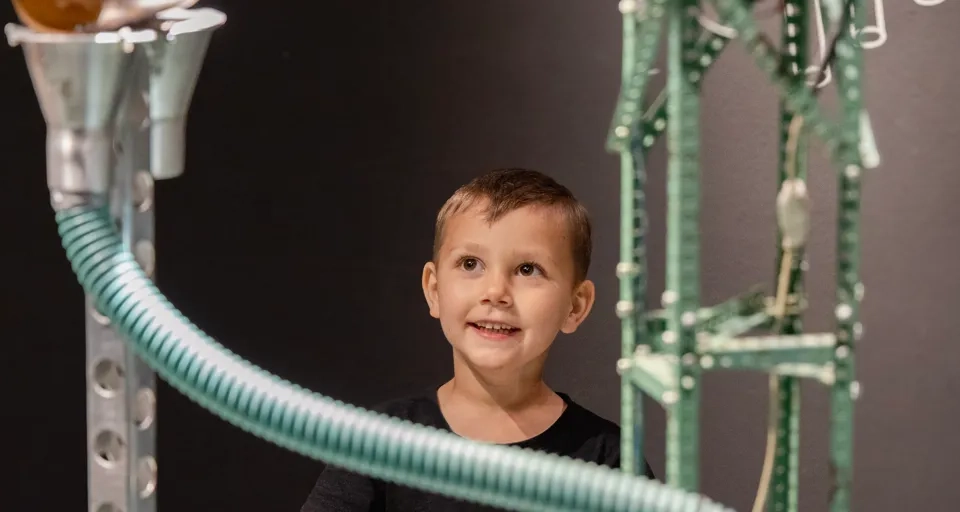 En ung pojke står framför en maskin.