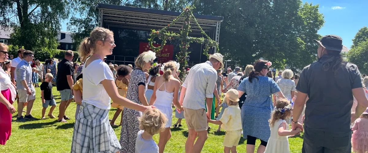 Människor som dansar runt en midsommarstång