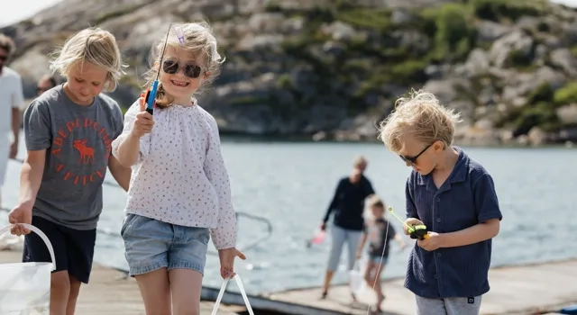 A group of young children standing on a pier next to a body of water.