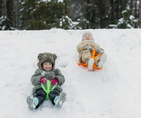 Två barn som åker pulka