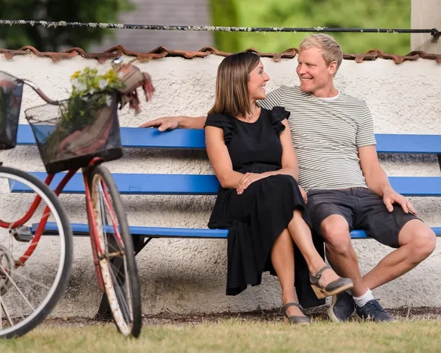 En man och en kvinna sitter på en bänk bredvid en cykel.