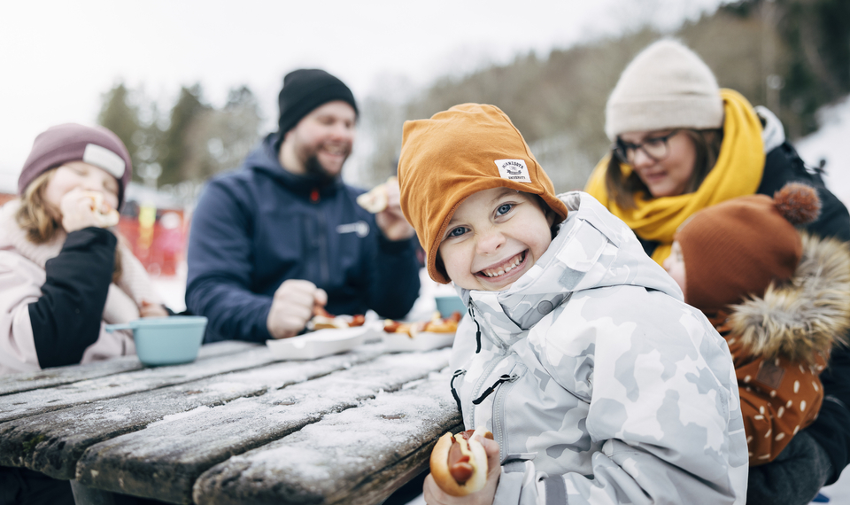 Familj tar en paus från skidåkning och äter en måltid.