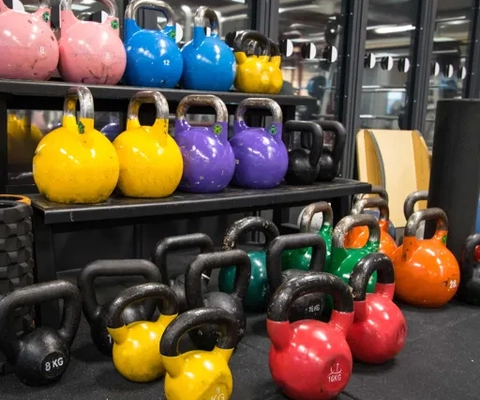 En rad färgglada kettlebells i ett gym.