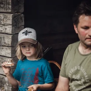 En pappa och son som sitter i ett vindskydd och fikar.