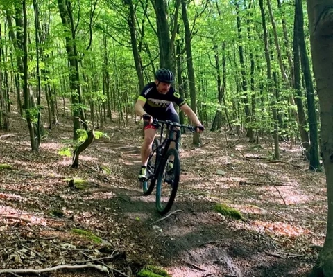 En man cyklar på en mountainbike genom en skog.