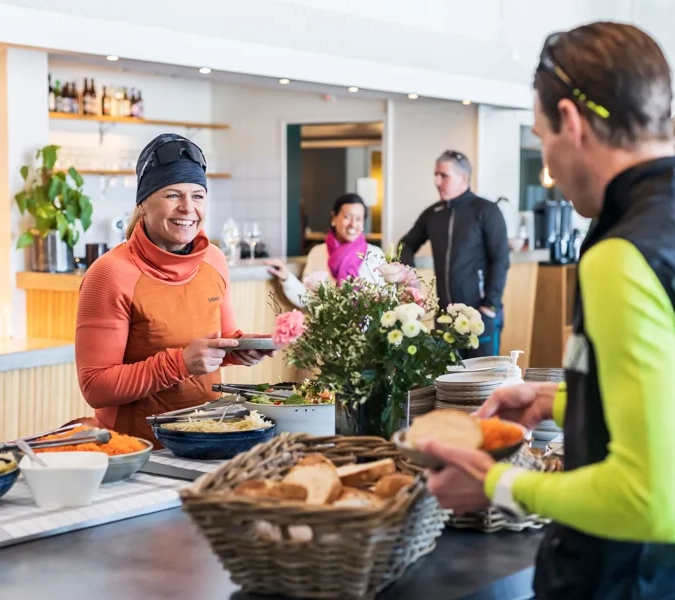 A group of people standing around a table filled with food.