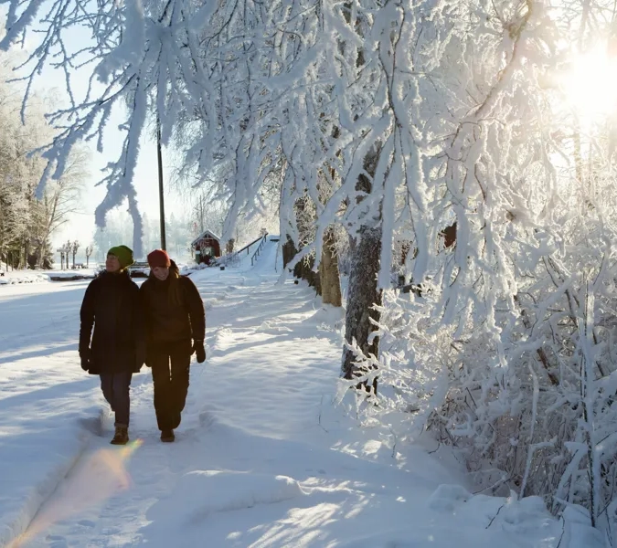 Två kvinnor promenerar i snön i sluss. 