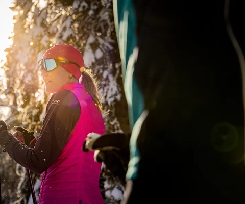Eine Frau in einer rosa Jacke steht im Schnee.