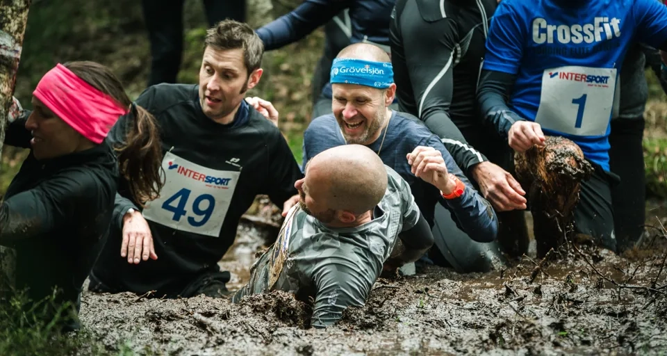A group of people in the mud in a forest.