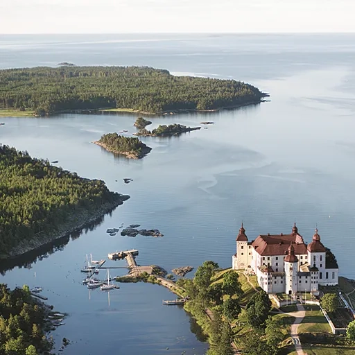 En flygbild över en skärgård och på den yttersta udden syns ett stort pampigt barockslott.