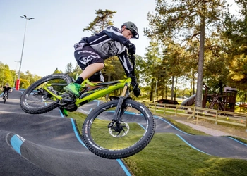 En man hoppar i luften med sin gröna cykel i Billingens Bikepark