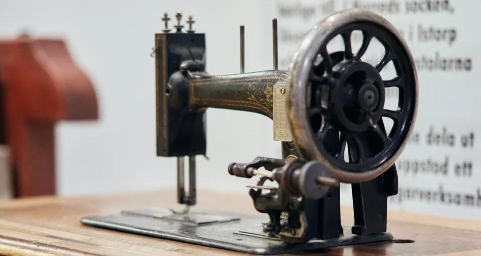 En symaskin som sitter på ett träbord.