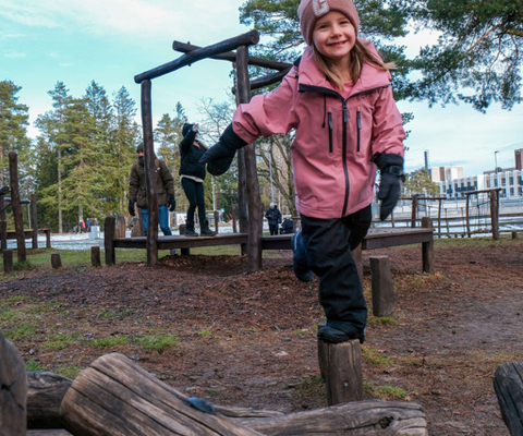 En ung flicka i rosa overall leker i en park