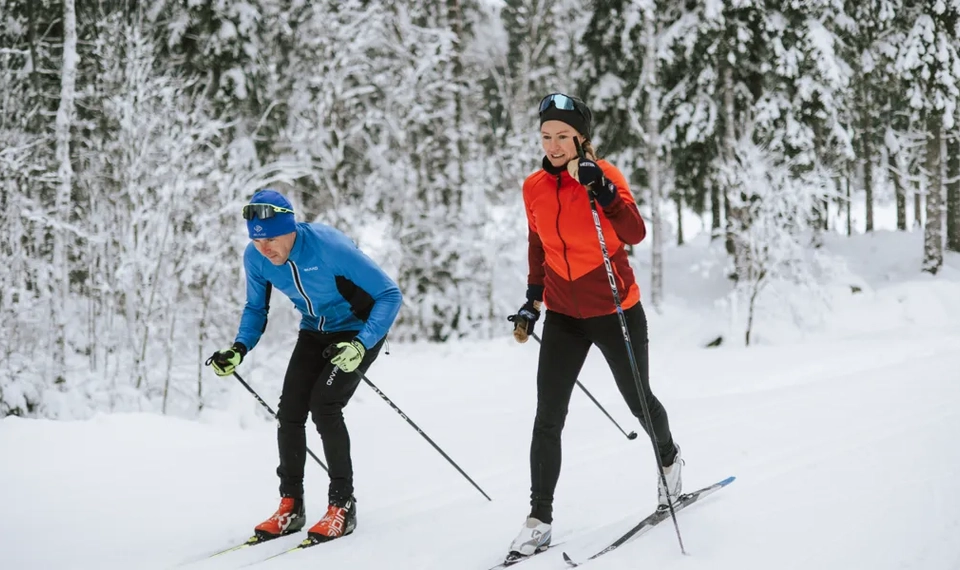 A couple of people riding skis down a snow covered slope.