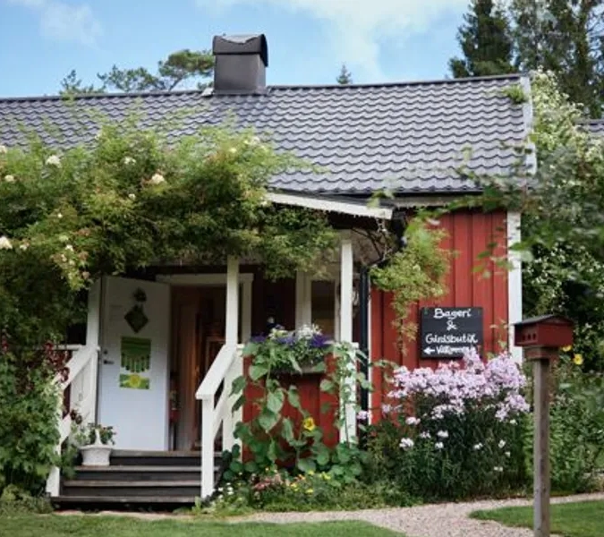 Ett litet rött hus med en vit veranda.