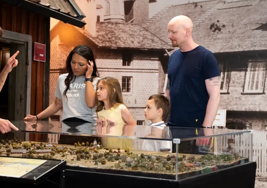 En grupp människor som står runt en modell över Tidaholm