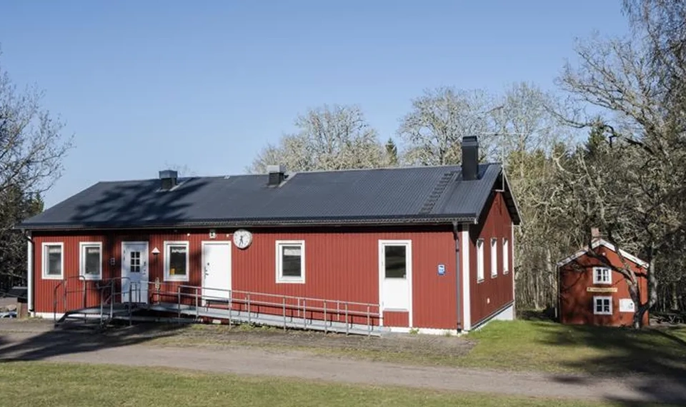Ein kleines rotes Haus, das mitten auf einem Feld steht.